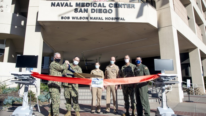 Military personnel standing in front of Naval Medical Center cutting a red ribbon