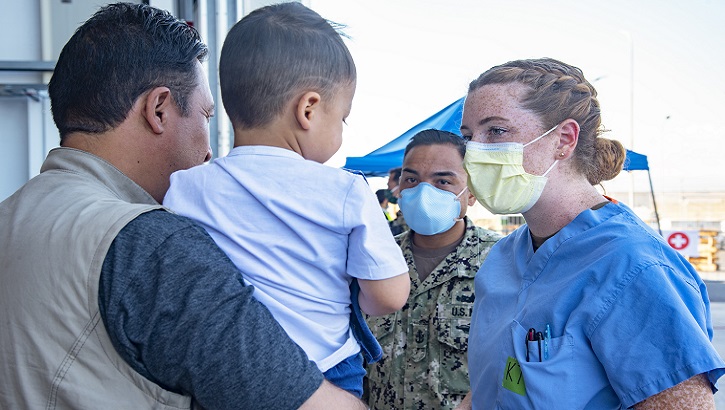 A Navy nurse speaks to a father and son.
