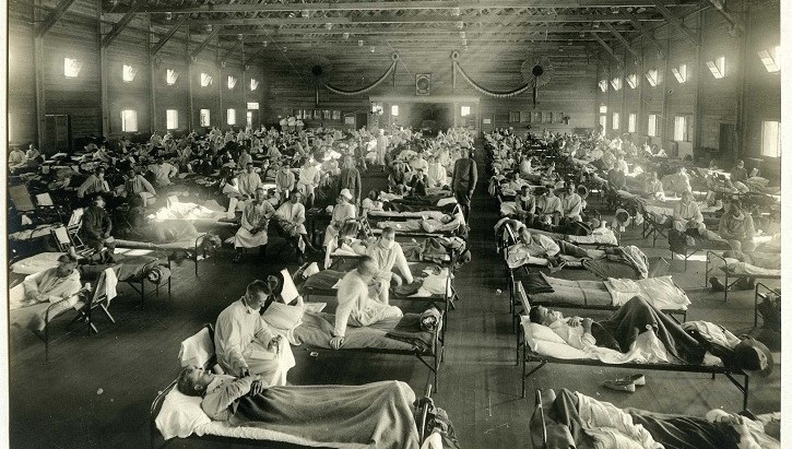 Black and white image of hospital beds lined up in rows, occupied by sick people