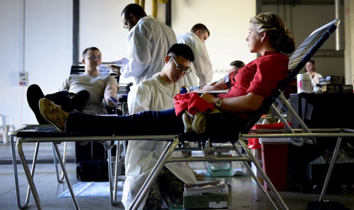 Army Spc. Hayeon McCurley, Landstuhl Regional Medical Center medical laboratory technician (kneeling), prepares Air Force Senior Airman Kimberly Gray, 31st Security Forces Squadron investigator, for donating blood during the Armed Services Blood Program blood drive at Aviano Air Base, Italy. 