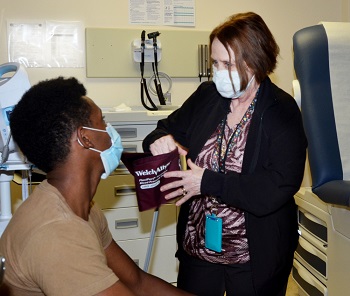 Military health personnel wearing a face mask checking a patients vitals