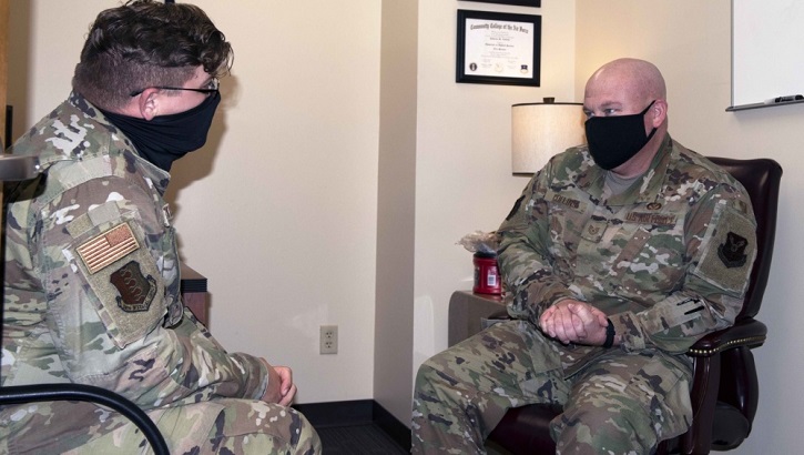 Image of Military personnel wearing face masks talking. Click to open a larger version of the image.