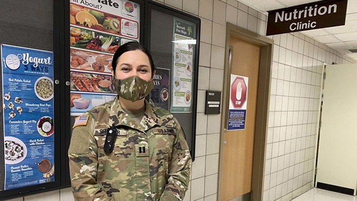 Image of Military personnel wearing a face mask standing in front of a Nutrition Clinic.
