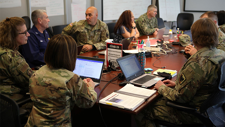 Image of Military personnel sitting around a table talking.