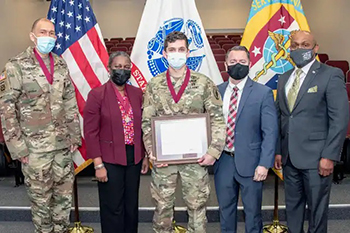 Military personnel wearing mask posing for a photo during an award ceremony