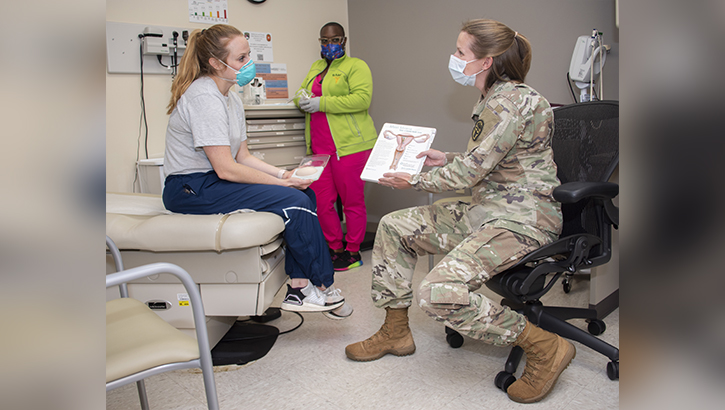 U.S. Army Maj. (Dr.) Kayla Jaeger, chief of Adolescent and Young Adult Medicine, discusses contraception options with a patient, U.S. Air Force Capt. Jacqueline Wade, while Benesha Jackson, a licensed vocational nurse, gathers instruments for an exam at the Capt. Jennifer M. Moreno Primary Care Clinic, Fort Sam Houston, Texas in 2021.  (U.S. Army photo by Jason W. Edwards)