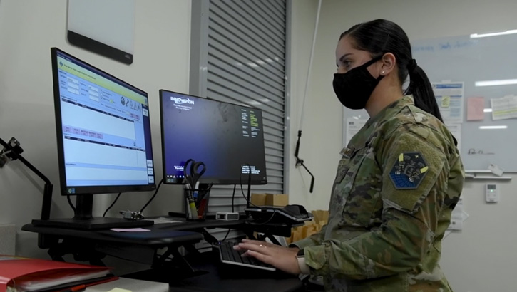 Military personnel typing on a computer