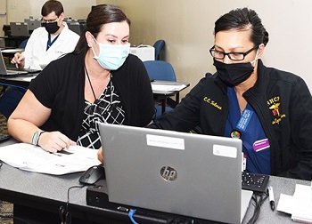 Military health personnel looking at a laptop computer screen