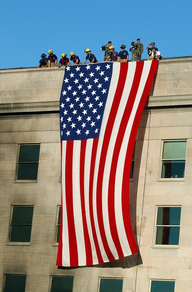 Link to Photo: Military Service members render honors as fire and rescue workers unfurl a huge American flag over the side of the Pentagon during rescue and recovery efforts following the Sept 11 terrorist attack. The attack came at approximately 9:40 a.m. as a hijacked commercial airliner, originating from Washington D.C.'s Dulles airport, was flown into the southern side of the building facing Route 27. (U.S. Navy photo by Photographer's Mate 1st Class Michael W. Pendergrass)