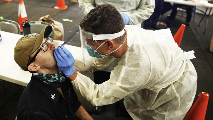 Hospital Corpsman administers a COVID-19 test to service member aboard the Wasp-class amphibious assault ship USS Essex.