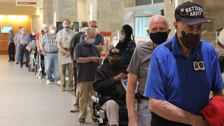 Image of nursing home members, wearing masks, waiting in a line to get their COVID vaccine. Click to open a larger version of the image. Click to open a larger version of the image.