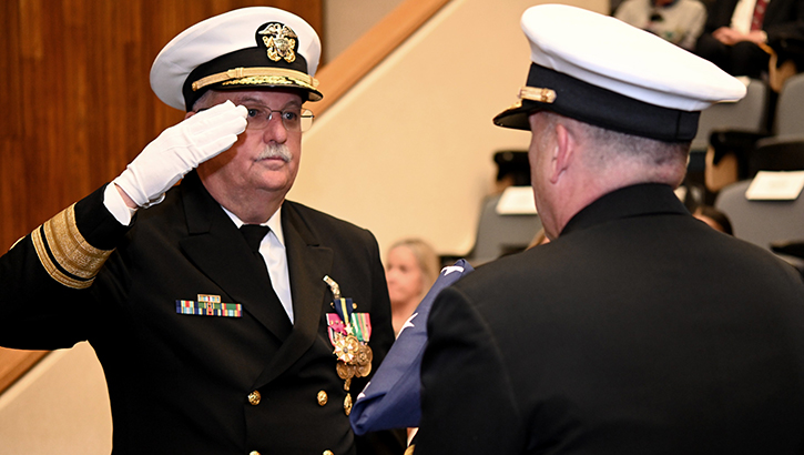 U.S. Navy Rear Admiral Bruce Gillingham salutes the American flag as U.S. Navy Rear Admiral Matthew Case presents it to him during a flag-folding ceremony for Gillingham's retirement event. (Photo by BUMED PAO)