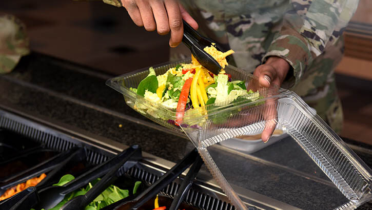 Image of A person serving himself a salad.
