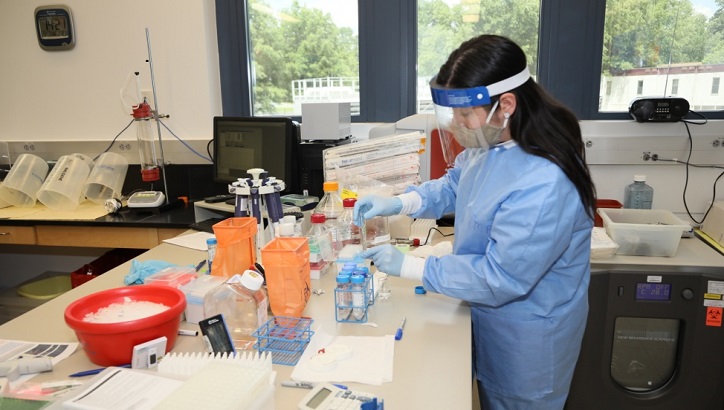 Image of Medical personnel in PPE, conducting lab tests. Click to open a larger version of the image.