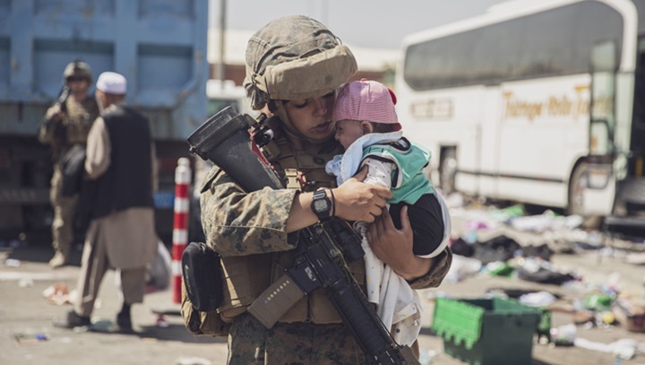 Image of A U.S. Marine carries a baby as the family processes through the Evacuation Control Center during an evacuation at Hamid Karzai International Airport, Kabul, Afghanistan, Aug. 28. (U.S. Marine Corps photo by Staff Sgt. Victor Mancilla).
