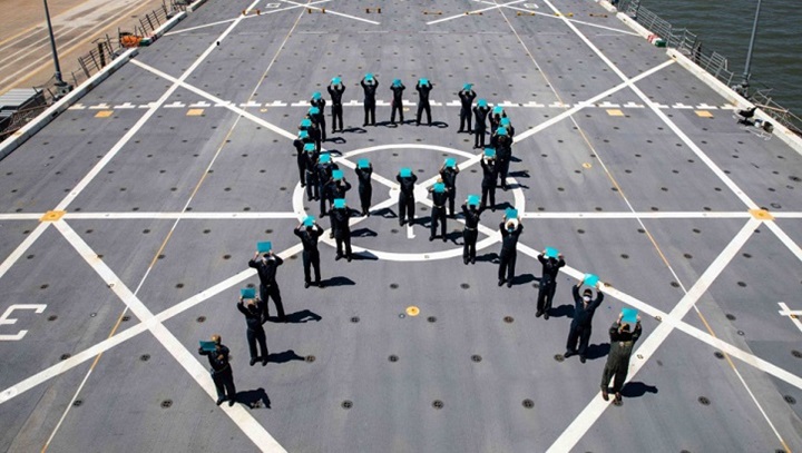 Image of Military personnel for a teal ribbon on a flight deck.