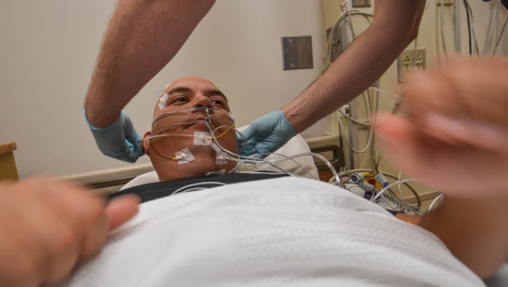 Image of A service member participates in a sleep study at Madigan Army Medical Center, Joint Base Lewis-McChord in Washington.  Sleep technicians connect 26 sensors to patients that measure eye and muscle movements, brain activity, heart rate, and breathing.