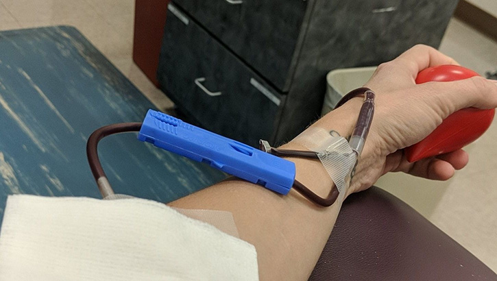 Image of Person's hand and arm, squeezing a ball, giving blood.