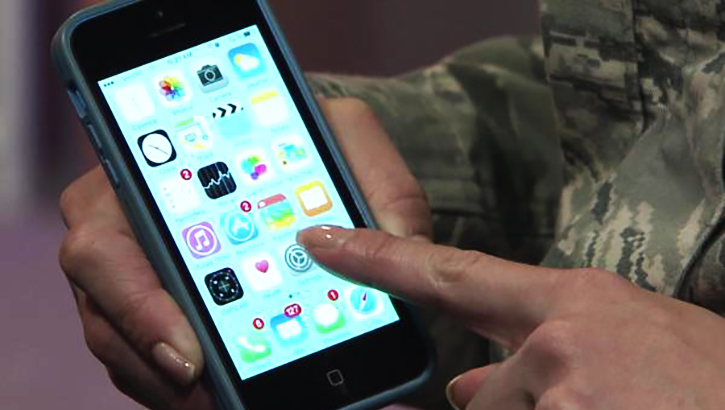 Image of soldier looking at his cell phone. Click to open a larger version of the image. Click to open a larger version of the image.