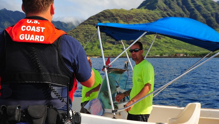 Image of Coast Guard employee talking with man on boat.