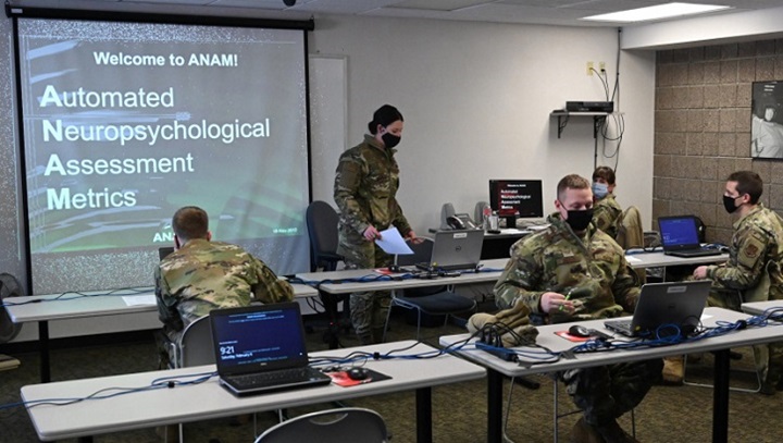 Image of A group of military personnel wearing face mask working on laptop computers.