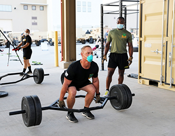 Military personnel, wearing a mask, lifting weights in a gym