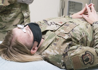 Military personnel wearing a face mask receiving treatment for headaches