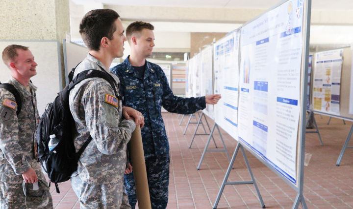 Army 2nd Lt. Mitchell Harris (second from left) and fellow medical students of the Uniformed Services University of the Health Sciences review posters depicting the latest research findings at Research Days, May 12, 2015.