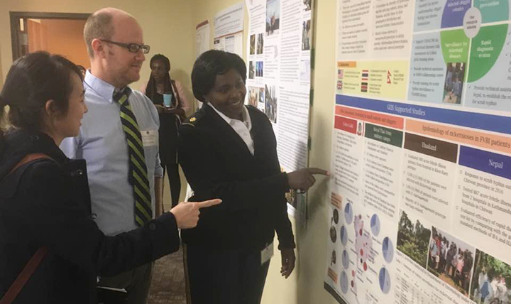 U.S. Army Major Elizabeth Wanja, deputy chief of the Department of Entomology at the Armed Forces Research Institute of Medical Sciences laboratory in Thailand, discusses poster of Armed Forces Health Surveillance Branch (AFHSB)-funded surveillance projects with Dr. Brett Forshey, lead for Global Emerging Infections Surveillance (GEIS) section Febrile and Vector-Borne Focus Area. (AFHSB photo by Briana Booker) 