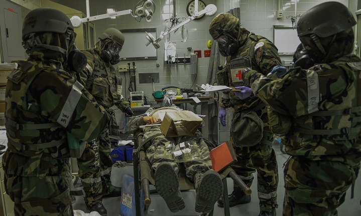 Airmen from the 51st Medical Operations Squadron (MDOS) simulate patient care in protective equipment during the Vigilant Ace 16 exercise. The MDOS participates in Vigilant Ace 16 to learn vital skills needed in the event of real-world contingencies. This exercise allows the MDOS Airmen to train in mission oriented protective posture, or MOPP, gear. (U.S. Air Force photo by Senior Airman Kristin High)