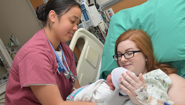 Image of Nurse hands mom her newborn baby.