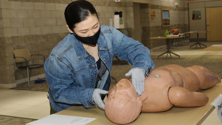 Image of Medical personnel, wearing a mask, practicing skills on a dummy. Click to open a larger version of the image.