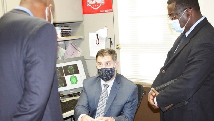 Image of Three physicians wearing masks; one sitting at a desk, two standing. Click to open a larger version of the image.