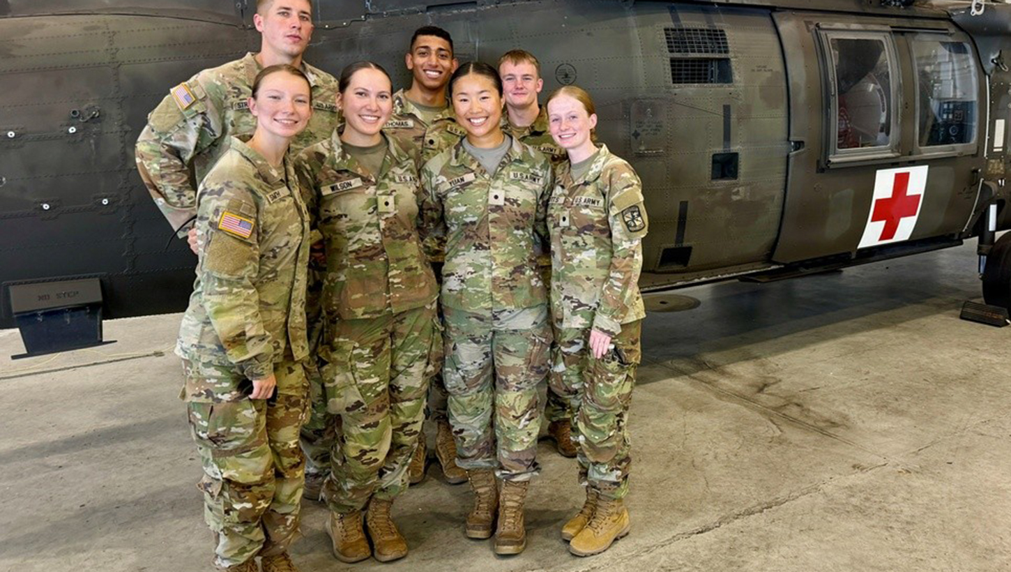 Army ROTC nursing cadets participating in the Army Nurse Summer Training Program pose for a group photo in front of a UH-60 Black Hawk medical evacuation helicopter
