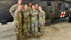 Army ROTC nursing cadets participating in the Army Nurse Summer Training Program pose for a group photo in front of a UH-60 Black Hawk medical evacuation helicopter