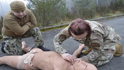 Under the watchful gaze of Navy Medicine Readiness Training Command Bremerton Tactical Combat Casualty Care instructors, 315th Aeromedical Evacuation Squadron personnel hone their medical response skills in treating traumatic injuries on the field of battle