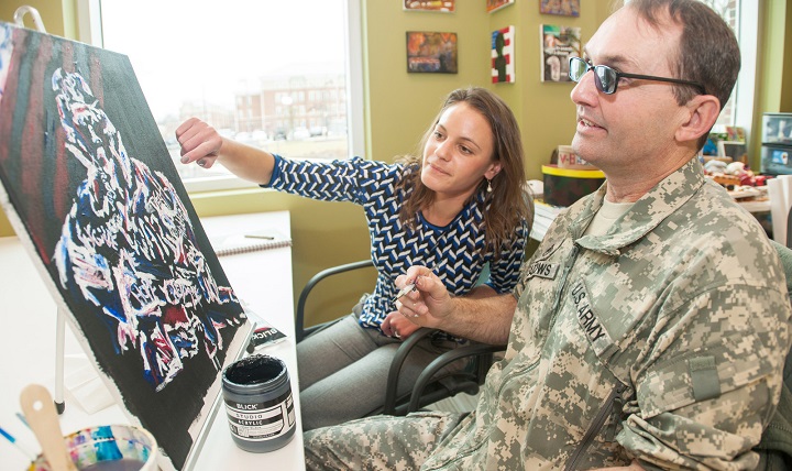 Army Staff Sgt. Jonathan Meadows and Jackie Biggs discuss a painting during an art therapy session at Fort Belvoir Community Hospital's traumatic brain injury clinic at Fort Belvoir, Va., Dec. 19, 2014. Meadows, assigned to Fort Belvoir's Warrior Transition Battalion, suffered a traumatic brain injury in 2012 when his vehicle rode over an improvised explosive device in Afghanistan. Biggs is an art therapist, and manages the program for Wounded Warriors in the TBI clinic. DoD photo by Marc Barnes