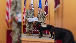 U.S. Army Col. Mark Stackle, Brooke Army Medical Center commander, presents Army Capt. Catherine Dorr with Air Force Staff Sgt. Scout’s certificate of promotion during a ceremony in the Carolyn D. Putnam Auditorium, BAMC, Joint Base San Antonio, Texas, Oct. 3, 2024. Staff Sgt. Scout was one of three facility dogs promoted during the ceremony. (DoD Photo by Garron Webster)