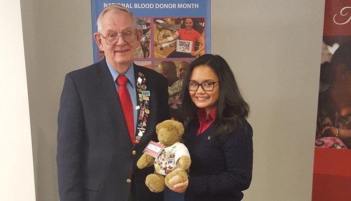 Al Whitney (left) and Jessica Escobar (right), management analyst for the Armed Services Blood Program, at the Armed Services Blood Program Office at Defense Health Headquarters in Falls Church, Va., Jan. 14. They are holding Ted E. Bear, a teddy bear that travels with Whitney everywhere he goes to help spread the importance of donating blood and blood products. The story behind Ted E. Bear began when Whitney bought a teddy bear for a young girl in need of a white blood cell donation.