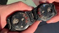 Two hands holding damaged wearable blast mesurement gauges from a study on blast pressure exposure.