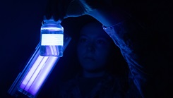 Hospital Corpsman Third Class Nikki Brown Wolff uses an ultraviolet light to inspect a water sample