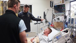 Cmdr. Daniel Hammer, left, maxillofacial surgeon and director of the Maxillofacial Restoration Program at Naval Medical Center San Diego, and Lt. Cmdr. Stephen Moreno, oral maxillofacial surgery residency program assistant director, check on U.S. Army Spc. Grant Dickerson in the intensive care unit two days after the performed his jaw-in-a-day surgery