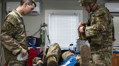 An Army medical evaluator assigned to Combined Joint Task Force–Horn of Africa, left, observes as Air Force Tech. Sgt. Alexander Julin, 776th Expeditionary Air Base Squadron medical technician, prepares trauma equipment while treating a simulated casualty during Exercise Pale Serpent 
