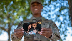 U.S. Air Force Senior Airman Cameron Richardson, 337th Air Control Squadron weapons technician, holds out a photo of his family 