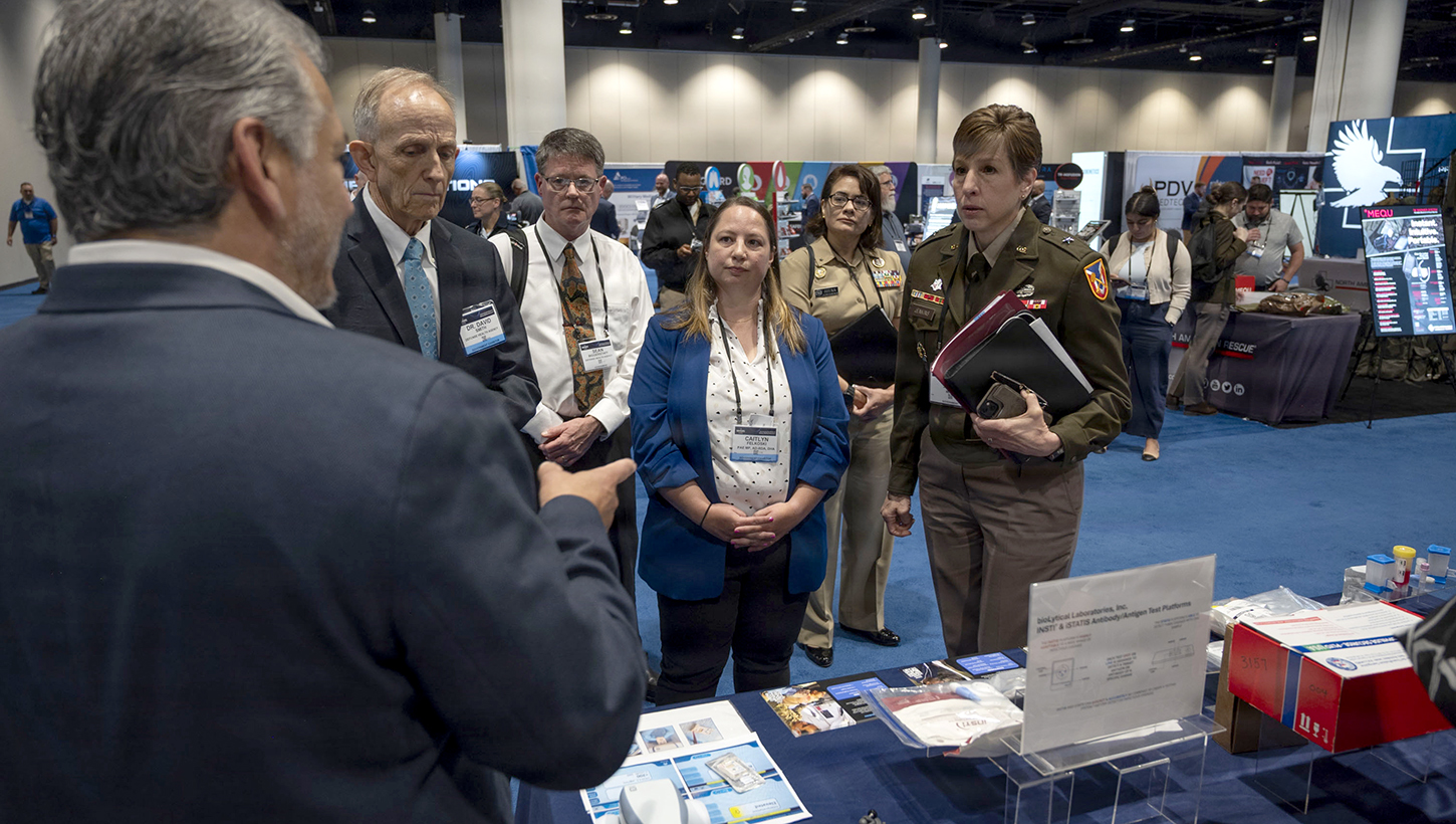Senior leaders with the Defense Health Agency tour the Research, Development, and Acquisition/Component Acquisition Executive office (AD-RDA/CAE) display during the Military Health System Research Symposium