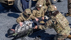 USU students move a simulated casualty onto a litter during the university's Gunpowder field exercise.