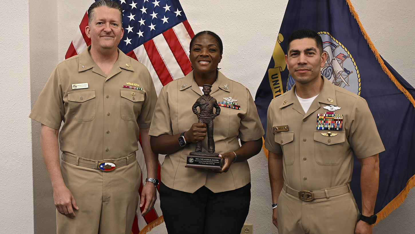 Rear Adm. Walter Brafford, left, commander, Naval Medical Forces Development Command (NMFDC), and Master Chief Hospital Corpsman Charles Padilla, NMFDC's acting command master chief, present Hospital Corpsman 1st Class Alisha Rogers, center, with a gift in recognition