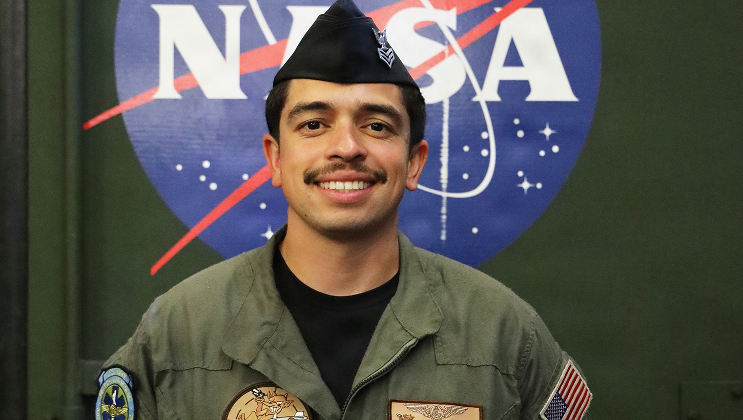 Hospital Corpsman 1st Class Brian Romero posing for a photo in front of the NASA logo