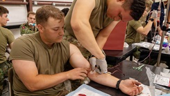 U.S. Army Cpt. Dan Walton, assigned to the Fort Hood Family Medicine Residency, inspects the needle inserted into the U.S. Army Soldier, Joseph Smith, assigned to Munson Army Health Center, to ensure the needle was put in safely