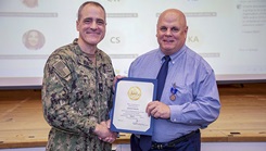 Rear Adm. Kevin Brown, commander, Naval Medical Forces Atlantic (NMFL), and director, Defense Health Network (DHN) - Atlantic, presents Gavin Wente, a financial specialist at NMFL, with a retirement certificate for 20 years of service during a joint DHN - Atlantic and NMFL all hands call held on board Naval Support Activity (NSA) Hampton Roads - Portsmouth Annex